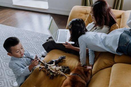 A mom checking her credit score in her laptop while her two kids is around her.