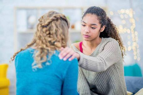 A woman sitting in her couch and talking to her friend, asking her to be her guarantor for a mortgage.