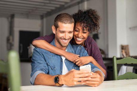 A woman hugging her partner and looked happy staring at their phone after getting their UK credit report for free.