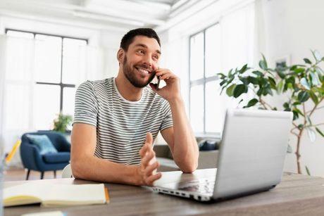 A man in front of his laptop and calling on his phone contacting ClearScore.