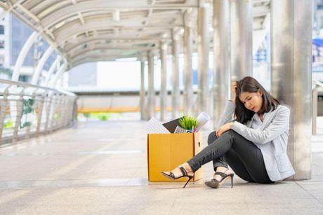 A woman with her stuff sitting down outside of her office after she got fired.