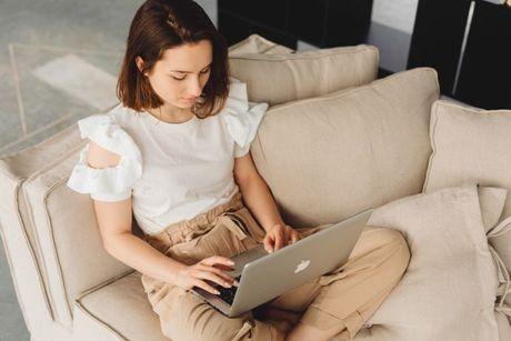 A young woman sitting on a couch, searching how to get her P60 online.