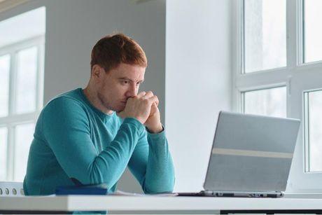 A man looking at her laptop searching if ClearScore is safe to use.