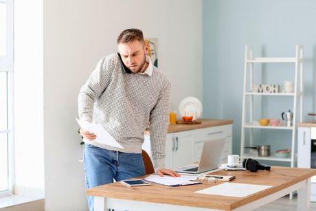 A young man looking at her documents and on a phone with a costumer service of Equifax.