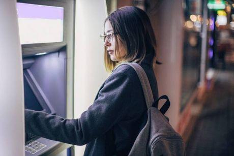 A woman in front of ATM at night, trying to use her arranged overdraft to withdraw cash.