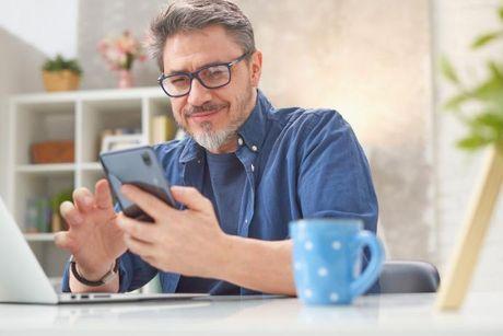 A man with in front of her laptop and phone searching information about TransUnion.