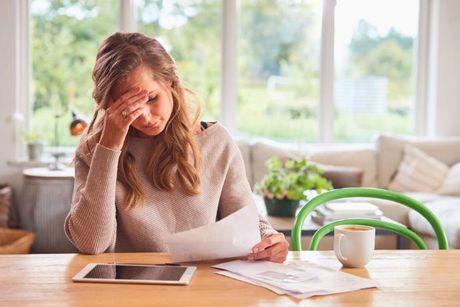 An image of woman looking at her documents and her tablet, trying to figure out what is a bank overdraft.