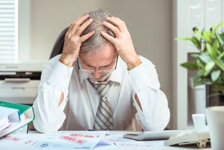 An old business man feeling stressed in his office after a bankruptcy.