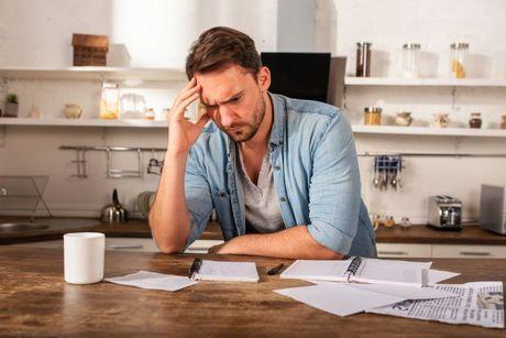 A man looking confused staring at his notes and bills wondering how to apply for a Barclays mortgage payment break.