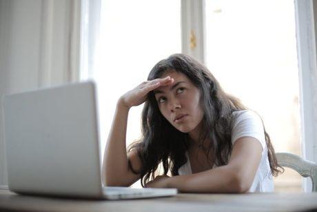 A girl looking confused in front of a laptop, searching information about universal credit.