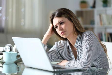 A girl looking confused in front of a laptop, and trying to search how to check Experian credit score for free.