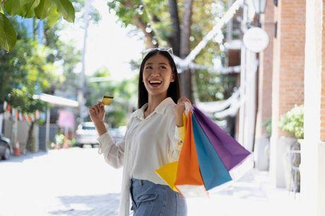 A girl holding a shopping bag and a credit card looking very happy after she increasing the credit card limit.