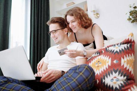 A couple looking at a laptop and some documents, searching for a Marbles credit builder card review.