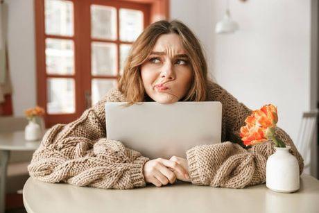 An image of woman with her laptop feeling unhappy after knowing her credit score band is Fair.