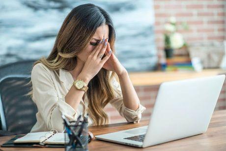 A young woman looking very worried and stressed in front of her laptop after getting a notification about a default after she missed a payment.