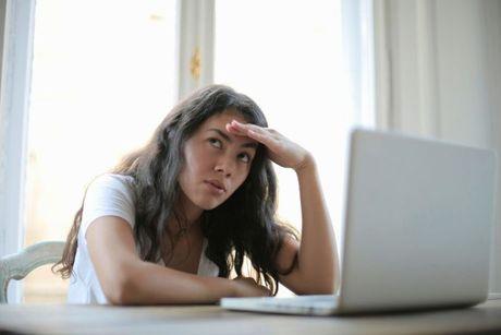 A young woman looking very worried wondering in front of her laptop, searching how Moneysupermarket credit check works.