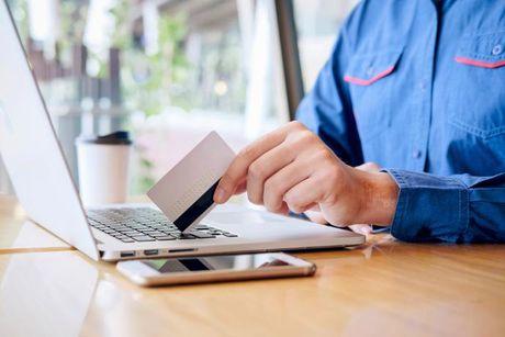 A man holding a credit card in front of his laptop and searching about Amazon credit cards.