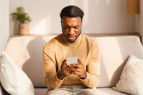 An image of a man using his phone looking confused to figure out what does a hard credit check mean.