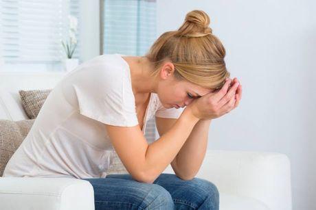 A woman sitting in her couch with her palm on her head feeling worried after getting an IVA (individual voluntary arrangement).