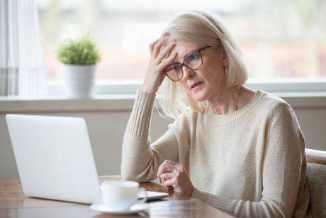 An image of old woman looking at her laptop, trying to figure out what is the Experian credit score range in the UK.