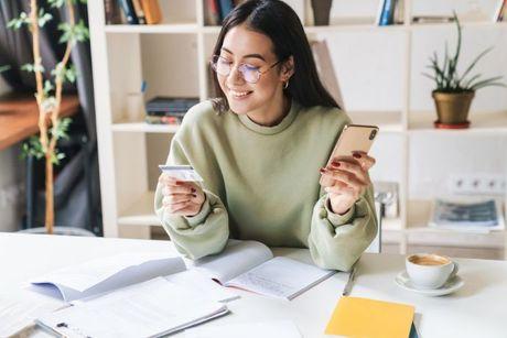 A girl holding a phone and searching for a review on Barclaycard forward credit builder card.