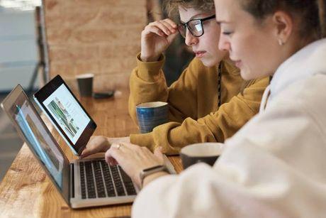 A woman in front of her laptop explaining to her friend about what is a good credit score.