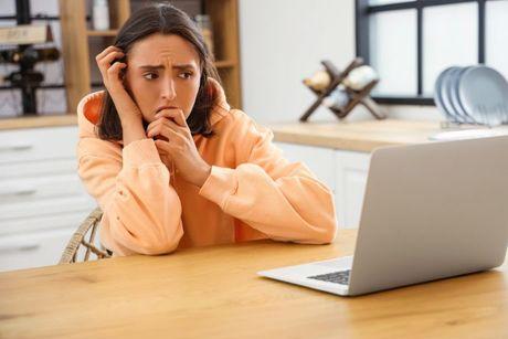 Young woman looking at her computer, afraid of identity fraud and considering a Cifas protective marker.