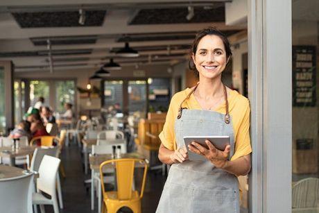 A woman small business owner in front of her restaurant. 