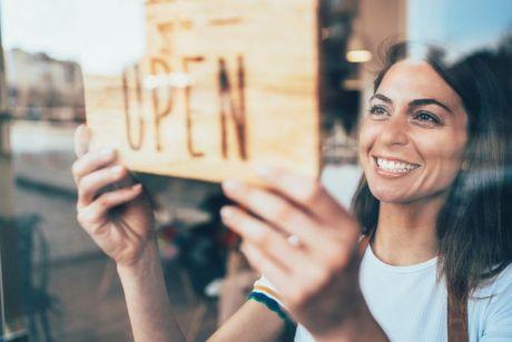 Young woman putting up an open sign for her new business.