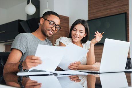 A couple looking at documents and laptop trying to understand how the MoneySuperMarket Credit Monitor work.