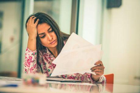 A girl feeling stressed looking at her documents and trying to figure out how to get a credit builder card with no credit check.