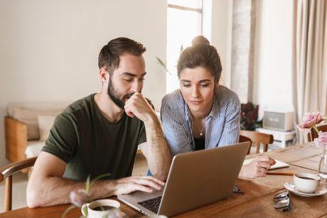 A couple sitting down in front of their laptop searching about how to check a credit score for free.