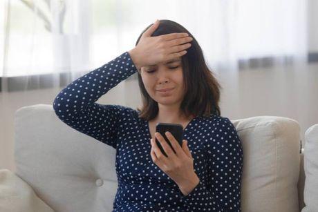 An image of sad confused lady on her phone, after she missed a insurance payment.