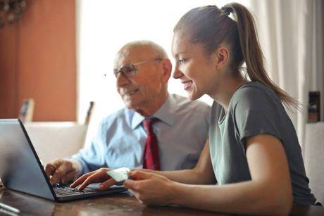 A woman in front of her laptop explaining to an old man about his credit score when he open a new credit account.