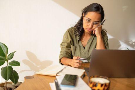 A girl looking confused in front of a laptop, reading an Argos credit card review.