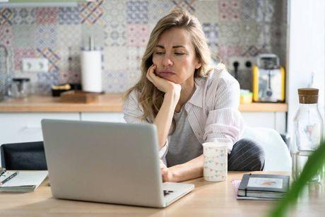 A woman sitting down in her living room and looking at her laptop and feeling annoyed because she can't login to Equifax.