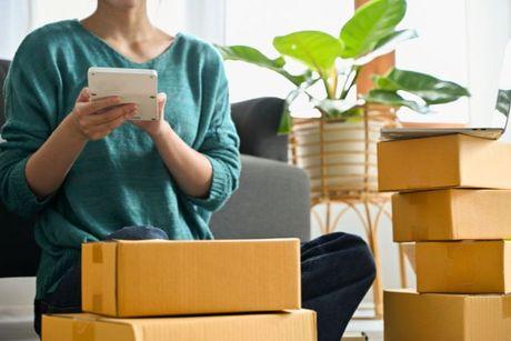 A young woman surrounded by moving boxes using a hand calculator to work out how much rent she can afford.