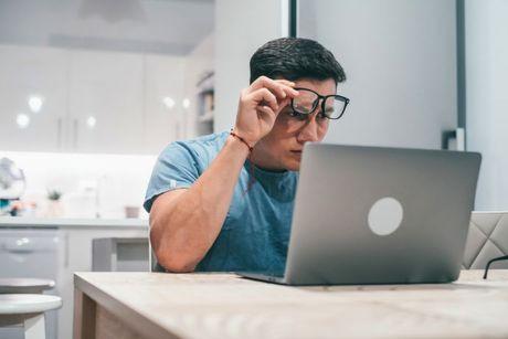 A man looking confused in front of his laptop figuring out how to check credit score with credit karma.