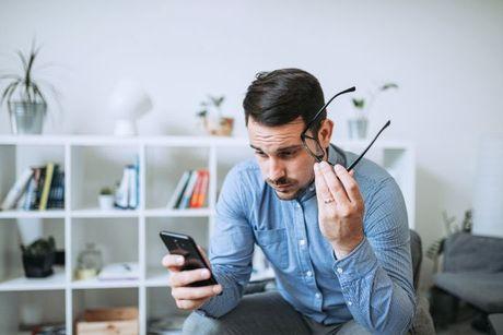 An image of a man using his phone looking confused to figure out what do the ClearScore rating bands mean.