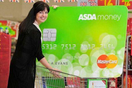 A woman holding an oversized ASDA Money Select card in a convenience store.