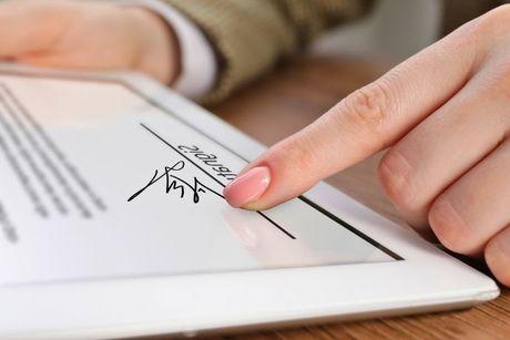 Hand of a person on an iPad, signing to be a rent guarantor on a tenancy agreement.