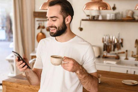 A man drinking his coffee while on his phone checking his UK credit score.