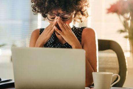 A young woman looking very stressed in front of her laptop after identity fraud.