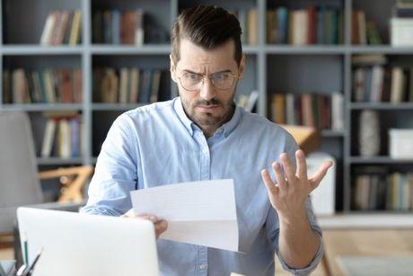 A man looking confused at his laptop and documents searching how the Equifax Statutory Credit Report works.