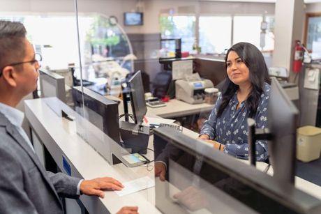 A woman in front of a front desk trying to opening a new current account.