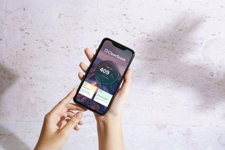 An image of someone holding a phone showing a ClearScore page on the screen.