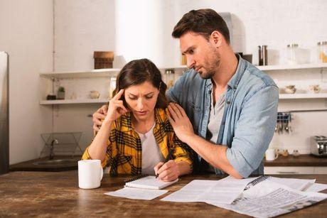 A picture of husband trying to comfort his wife who is stressed on a call, figuring out how to get a loan with bad credit.