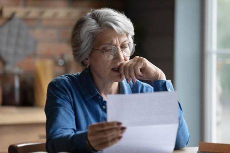 An image of old woman looking at her documents, trying to figure out what is a Country Court Judgment (CCJ).