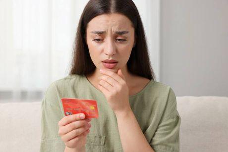 A woman holding her credit building card feeling confused because she doesn't know what to do with it.