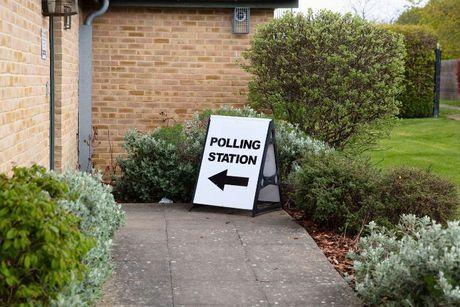 Image of a sign pointing towards a polling station, where UK residents can exercise their right to vote.